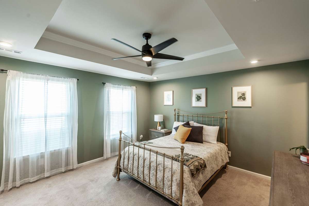Spacious primary bedroom painted in a calming soft green, creating a serene retreat for rest and relaxation.