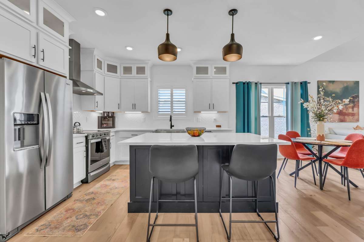 The oversized island provides ample seating and prep space—ideal for entertaining or casual family gatherings—while the stainless steel appliances and custom vent hood add a touch of sophistication. It has bright under counter lights and pendants!
