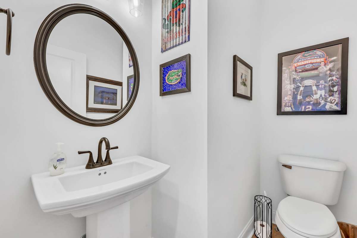 A classic pedestal sink paired with a sleek bronze fixture creates a timeless feel, while the round framed mirror adds a touch of elegance in the powder room!