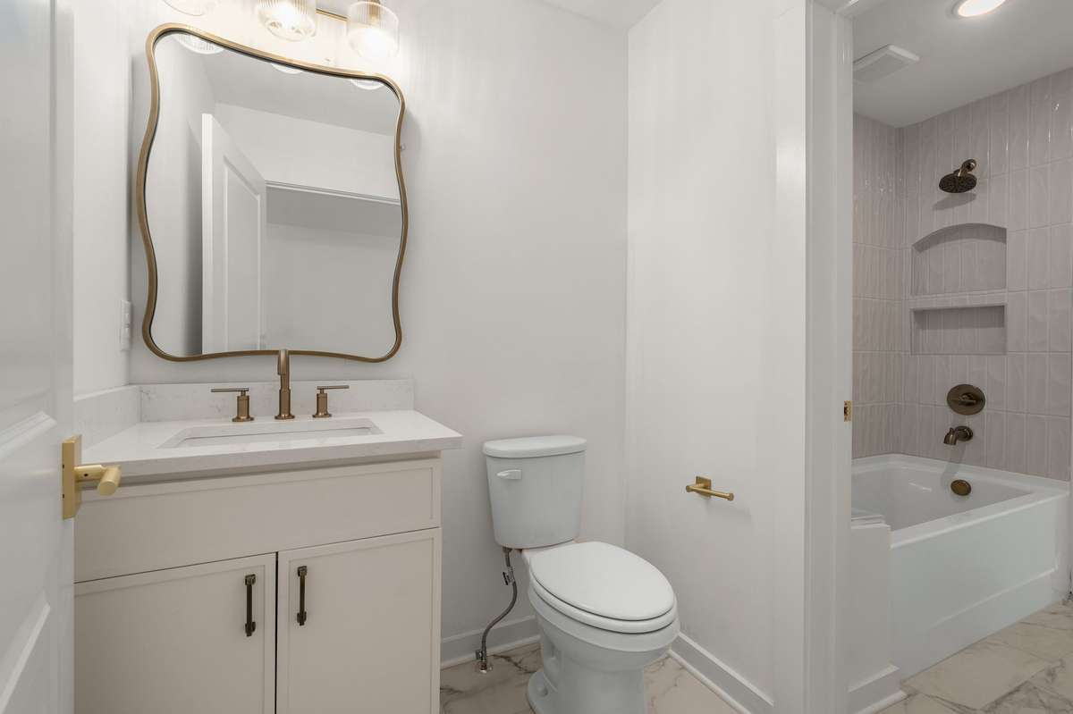 Secondary bathroom which features two vanities and connecting via tub / shower combo