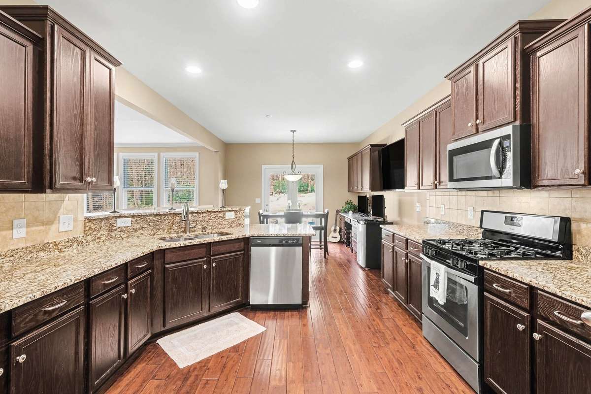 Spacious kitchen with granite countertops, abundant cabinetry, and stainless steel appliances, opening to a bright dining area—perfect for everyday living and entertaining.