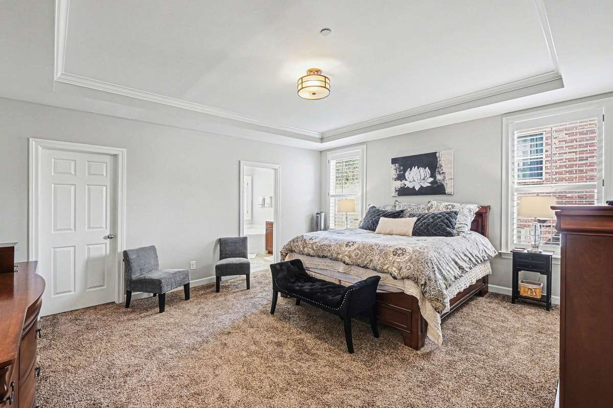 Spacious primary bedroom featuring brand new plush carpeting, a tray ceiling, and abundant natural light.