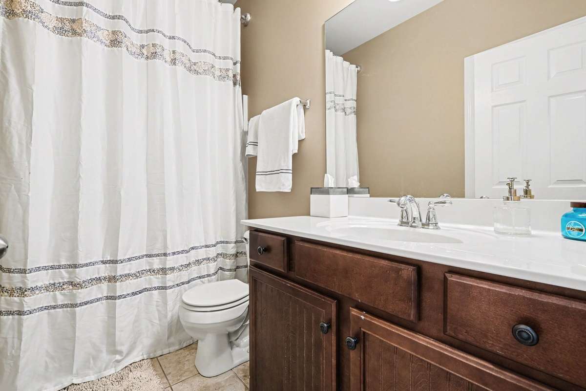 Well-appointed main-level hall bath featuring a spacious vanity with ample storage, neutral finishes, and a full tub/shower combination. Designed for both convenience and comfort, ideal for guests and everyday use.