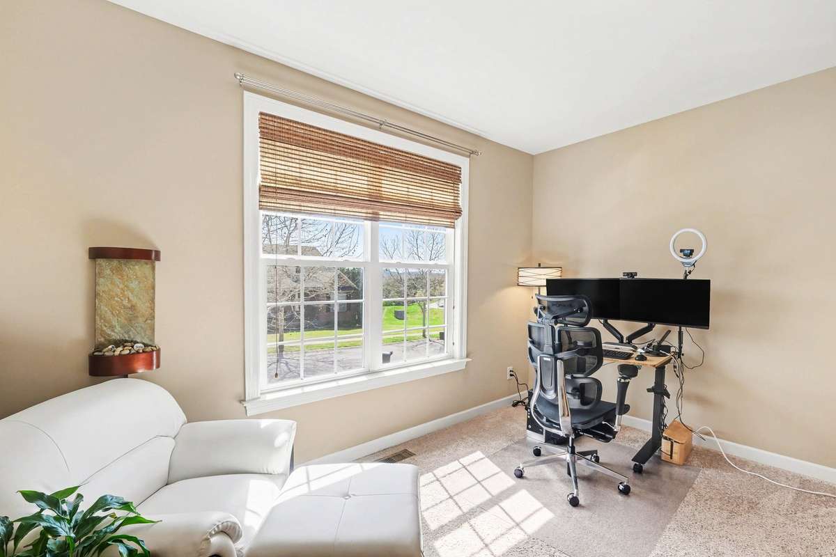 Bedroom 2 is Sun-filled and on the main-level featuring large windows, plush carpeting, and warm neutral tones.