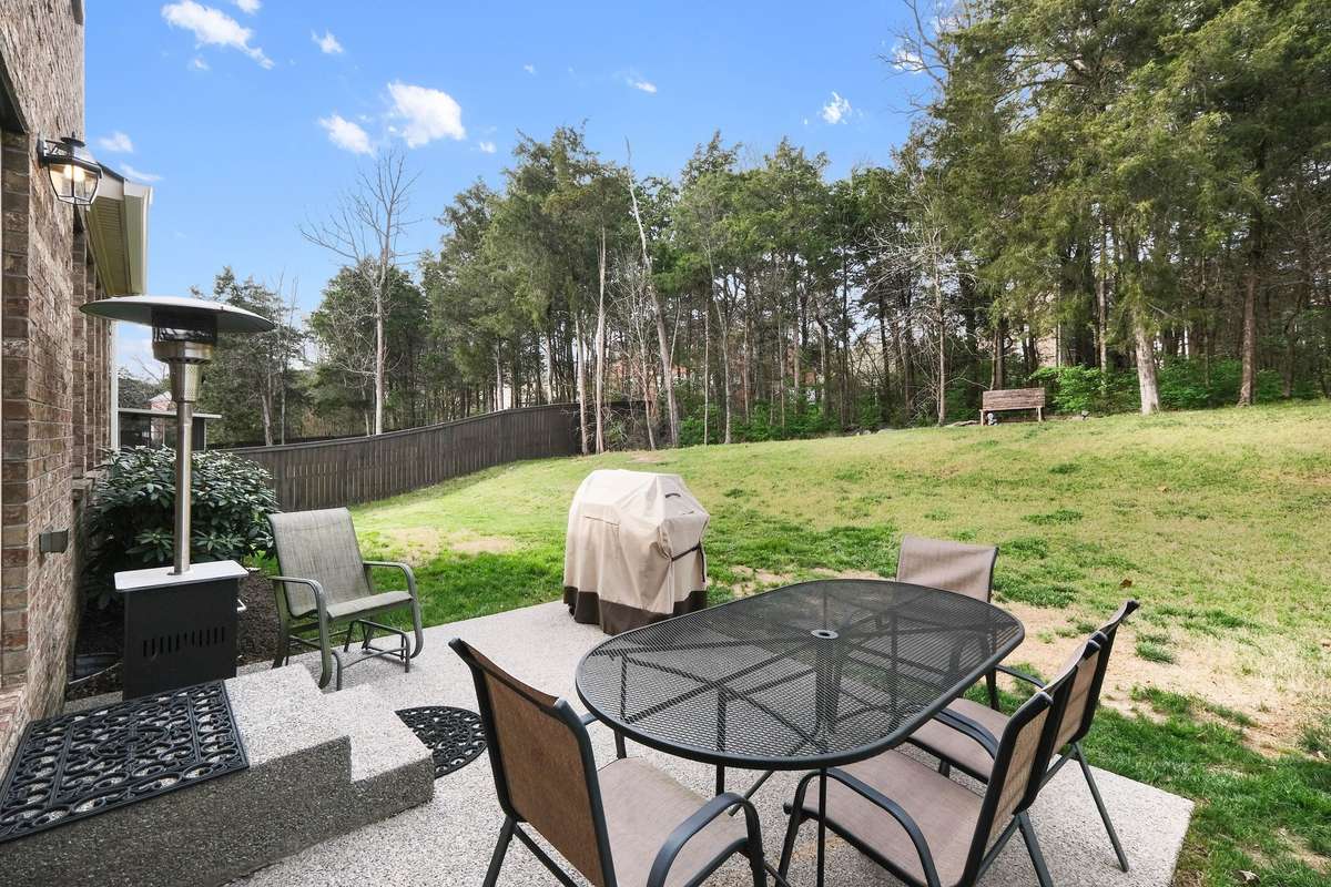 Enjoy outdoor living on this private patio overlooking a spacious, tree-lined backyard. Perfect for grilling, dining, or relaxing, this serene setting offers both open green space and natural privacy.