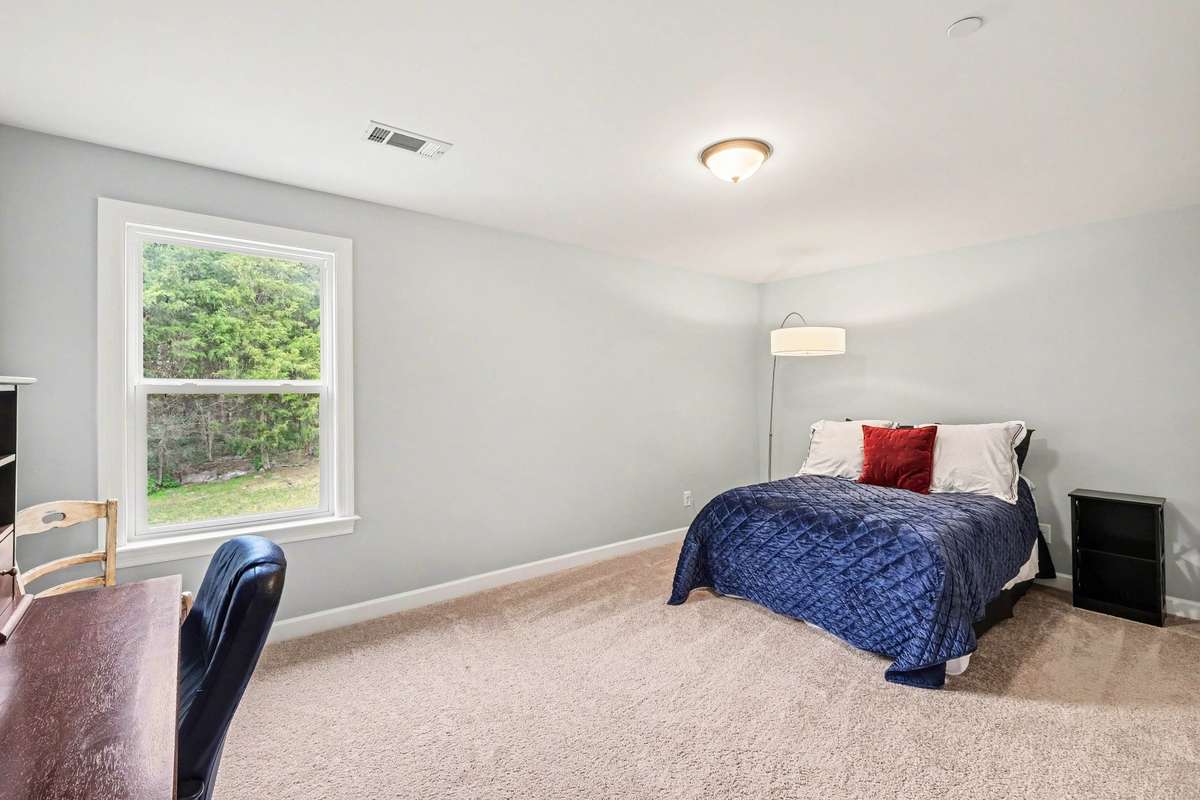 Tucked away upstairs, bedroom 5 offers a quiet retreat with expansive floor space and a large window that brings in peaceful, tree-lined views. The open layout easily accommodates a variety of uses, from a guest suite to a productive workspace