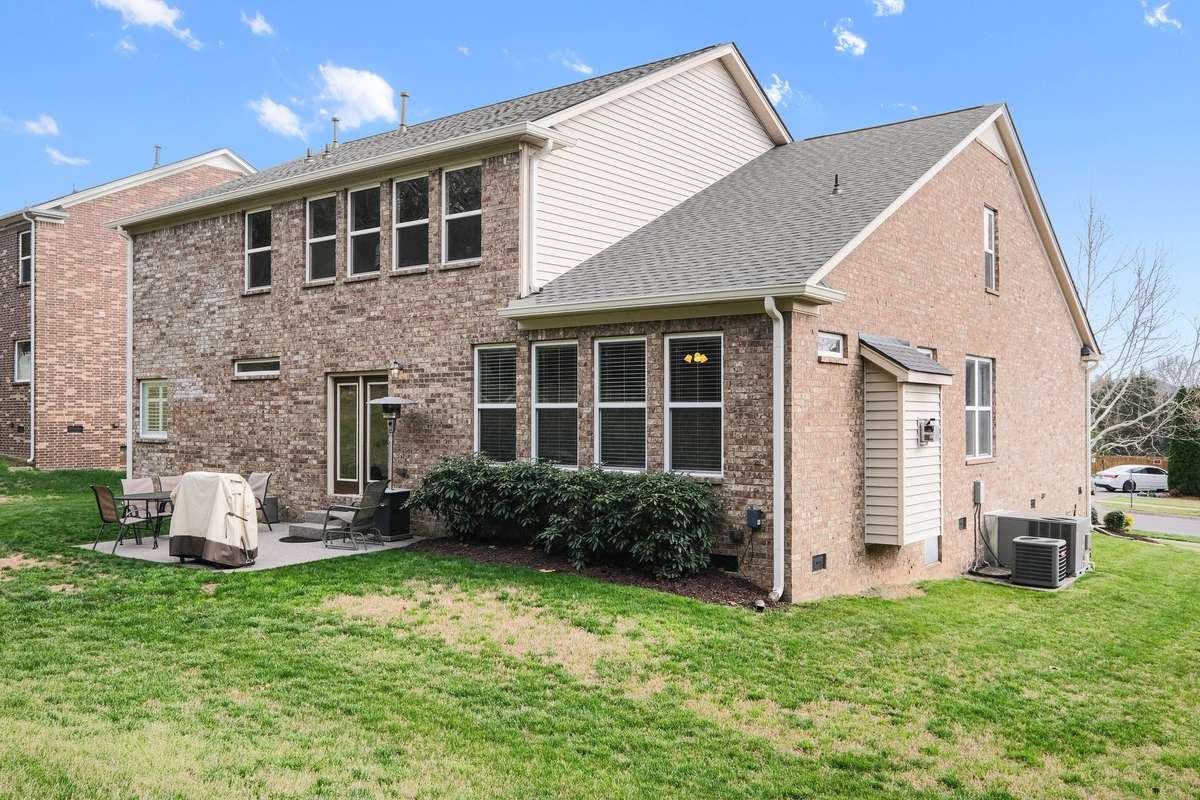 Attractive rear elevation showcasing a combination of brick and siding, complemented by a well-sized backyard and patio area. Ideal for grilling, outdoor dining, or simply unwinding in a comfortable and private setting.