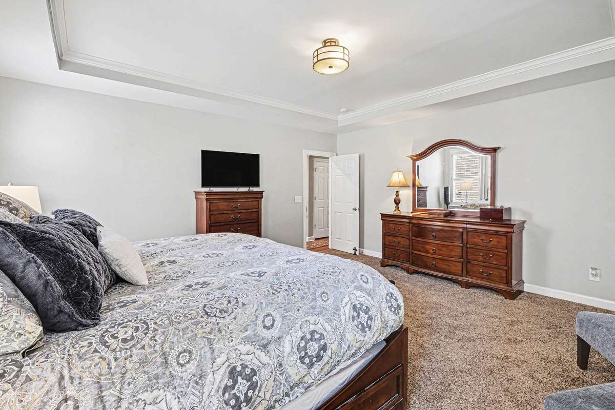 Another view of the primary bedroom offering plenty of space for a sitting area, complemented by neutral tones and a seamless connection to the private ensuite for a relaxing retreat.