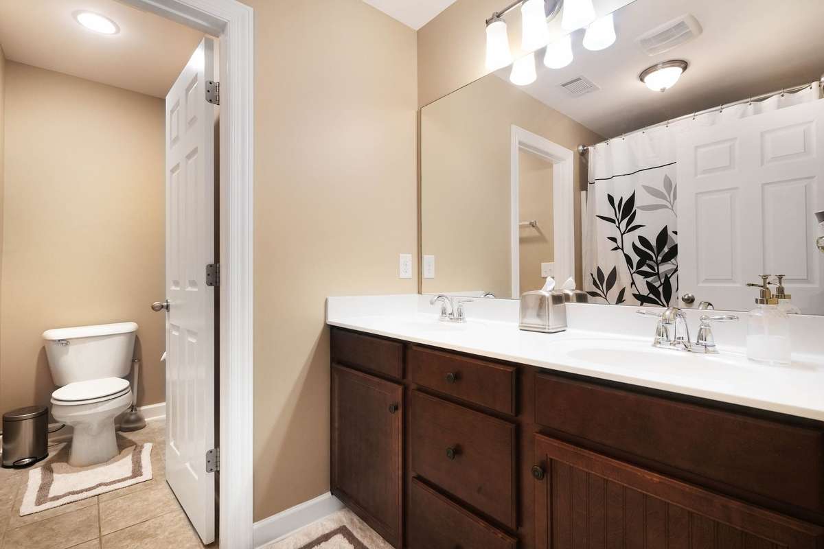 Upstairs hall bath featuring a dual-sink vanity, ample counter space, and a separate water closet with tub/shower combination—designed for easy sharing and everyday convenience.