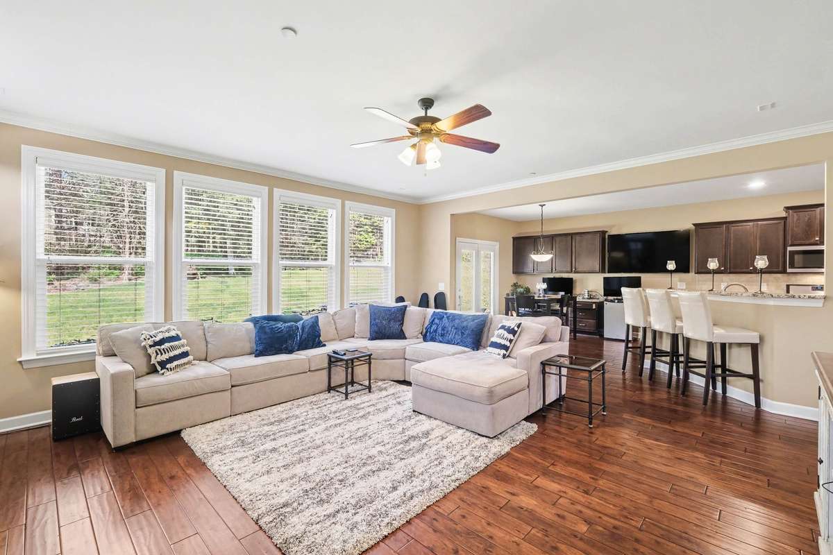 Bright, open-concept living space filled with natural light, featuring beautiful hardwood flooring and seamless flow into the kitchen with bar seating—ideal for modern living and effortless entertaining.