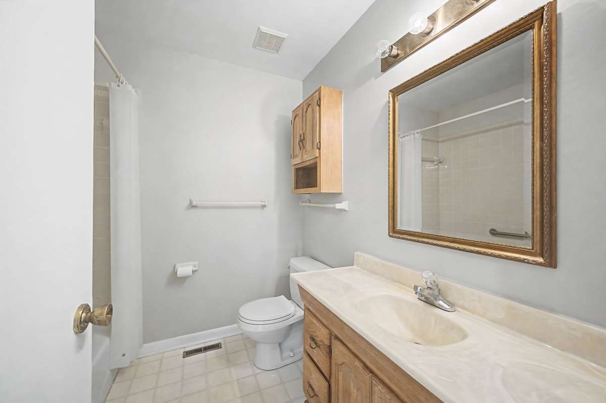 Hall bath with vinyl floor and tile surround in shower/tub combo.