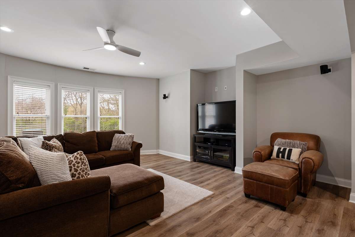 The basement TV area has a ceiling fan, speakers and tons of windows