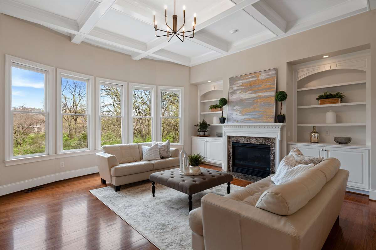 The elegant, formal living room hosts a wall of bay windows to bring the outside in