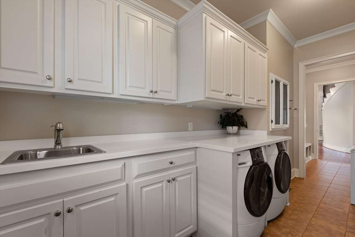 The side entrance to the home brings you into the large laundry room. You'll enjoy an abundance of cabnetry and built in sink. Plenty of counter space to fold clothes, etc