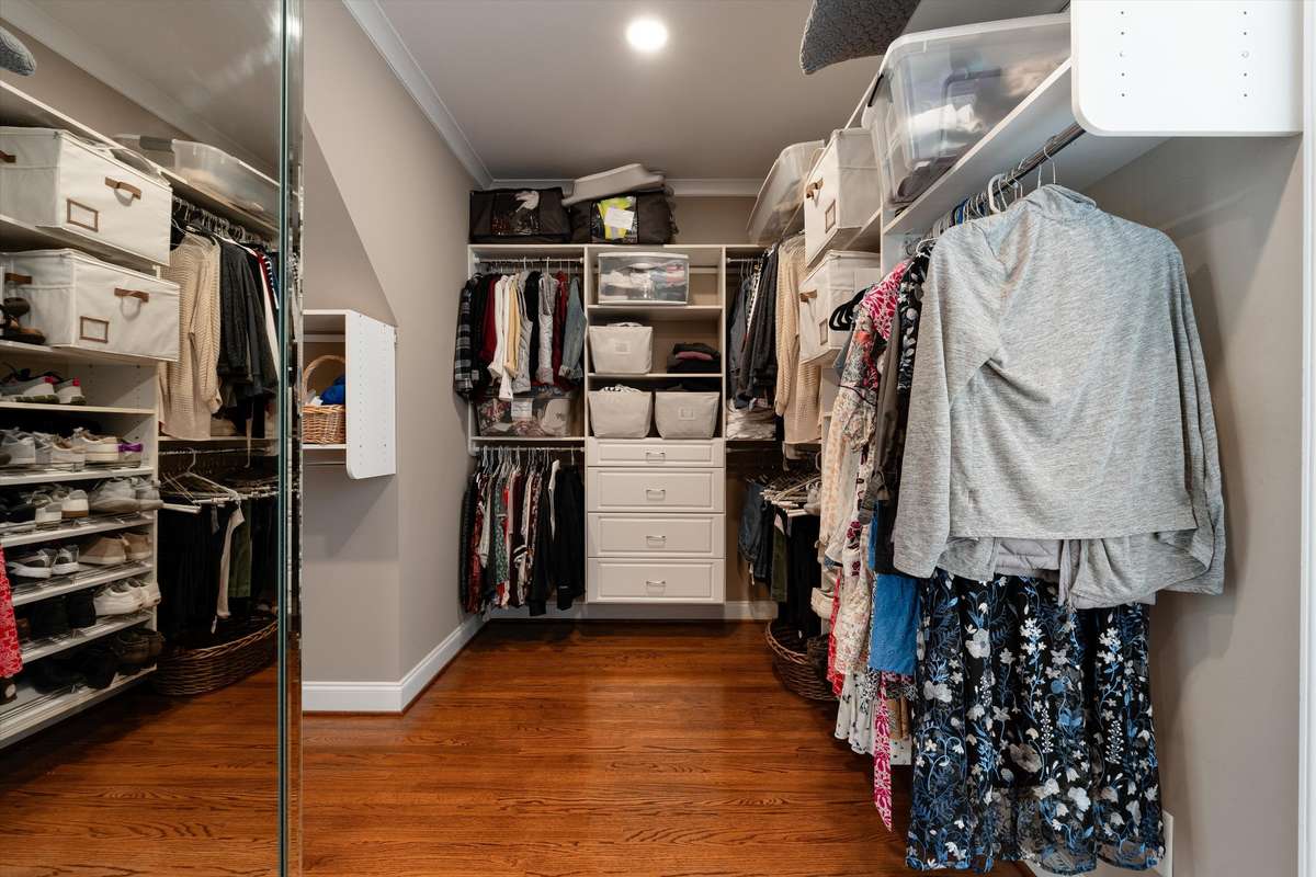 Primary closet has multiple built-ins, a mirrored wall and storage drawers