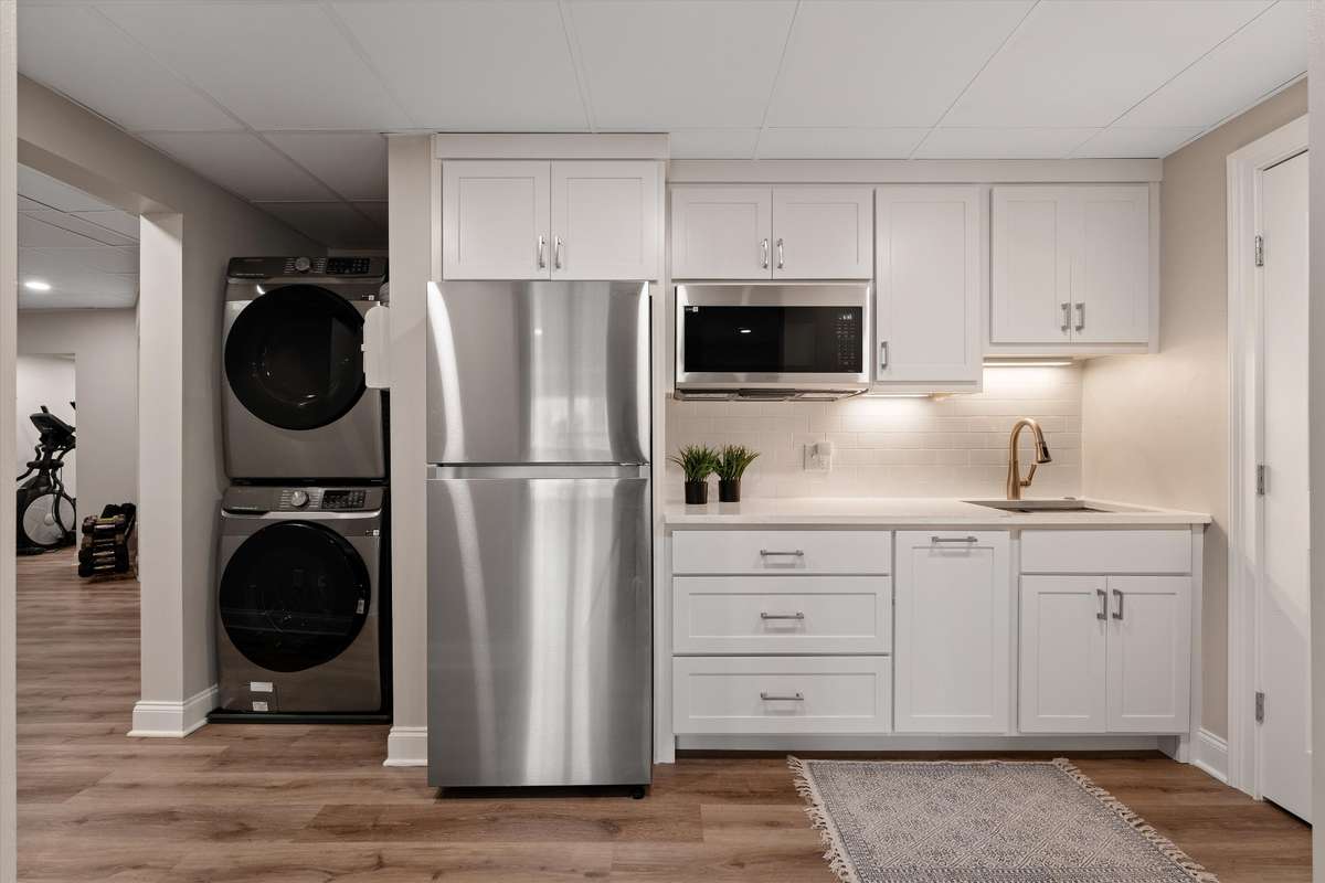 The full walk out basement has a kitchenette with refrigerator, convection microwave, sink, storage and washer dryer