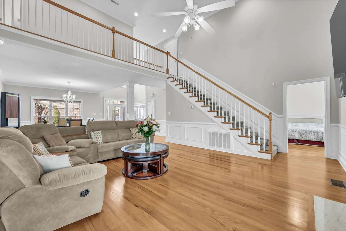 Spacious Living Room w/ a 18' Ceiling & Elegant Stairway