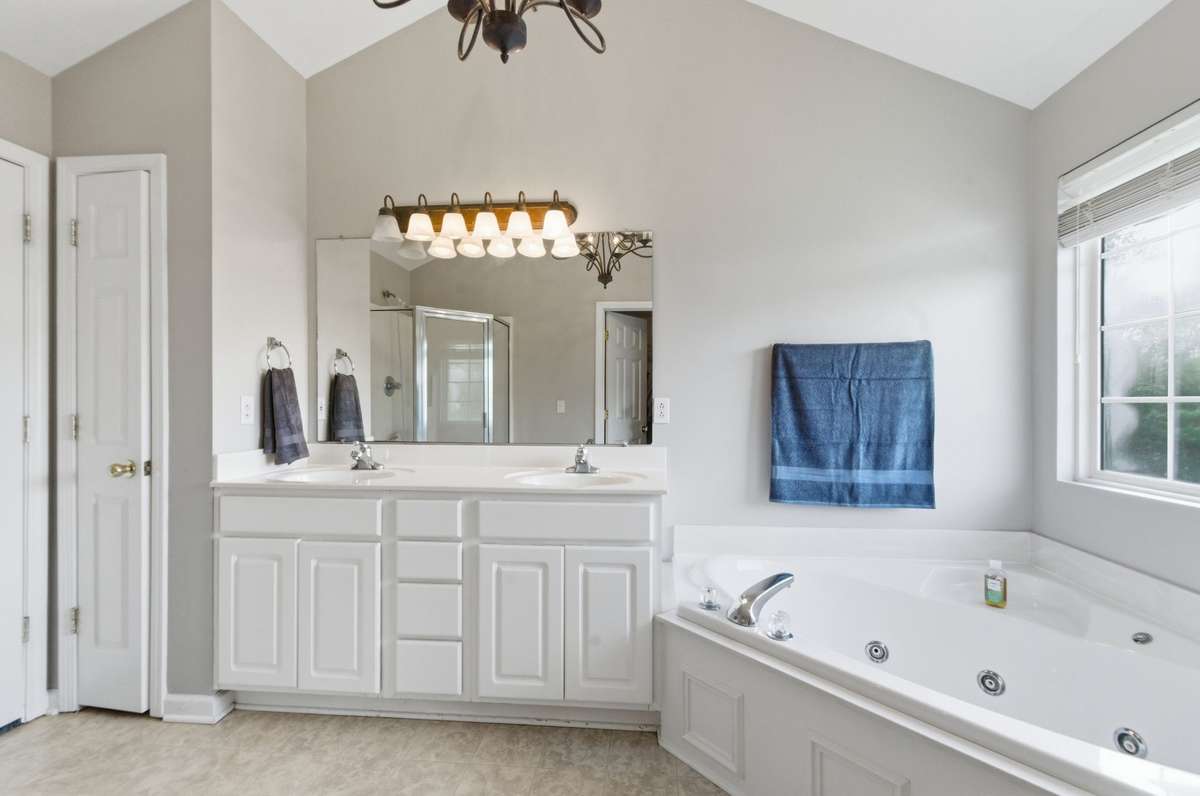 Spacious en-suite bath featuring a double vanity, soaking tub, and separate shower for added comfort.