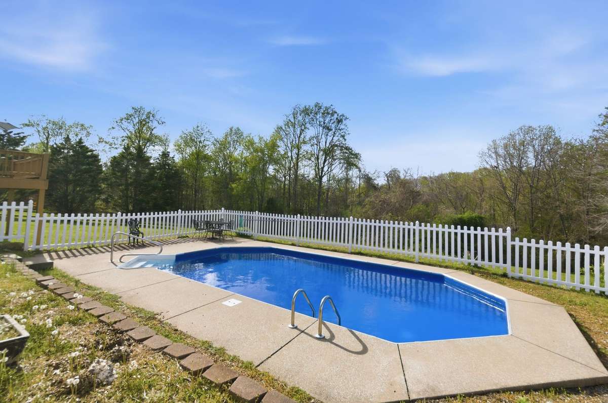 Inviting pool area with ample room for lounging and entertaining, all set against a peaceful tree-lined backdrop.