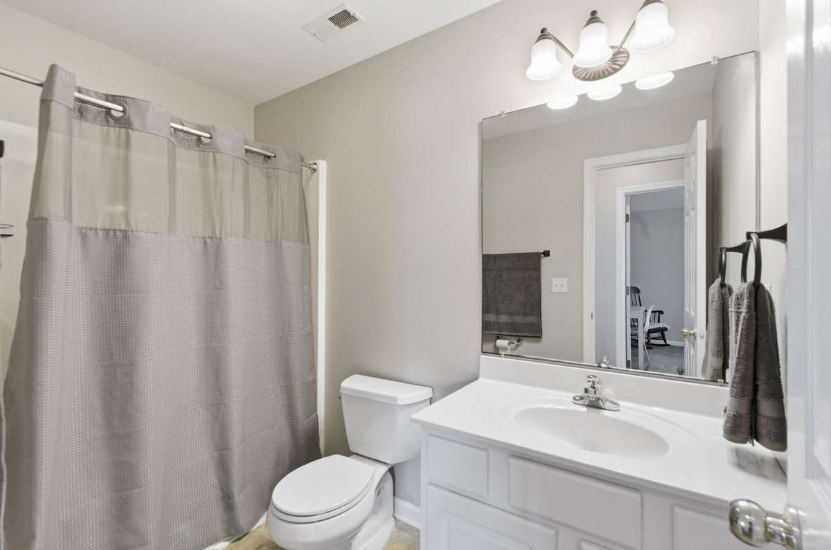Clean and bright bathroom with a large vanity, updated lighting, and a shower/tub combination.