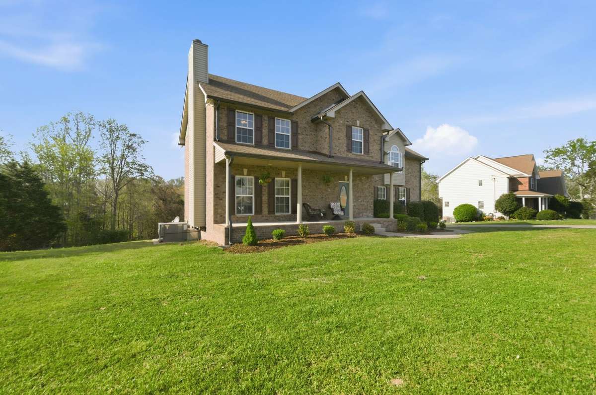 Expansive front yard and angled view showcase the home’s scale and peaceful setting with surrounding greenery.