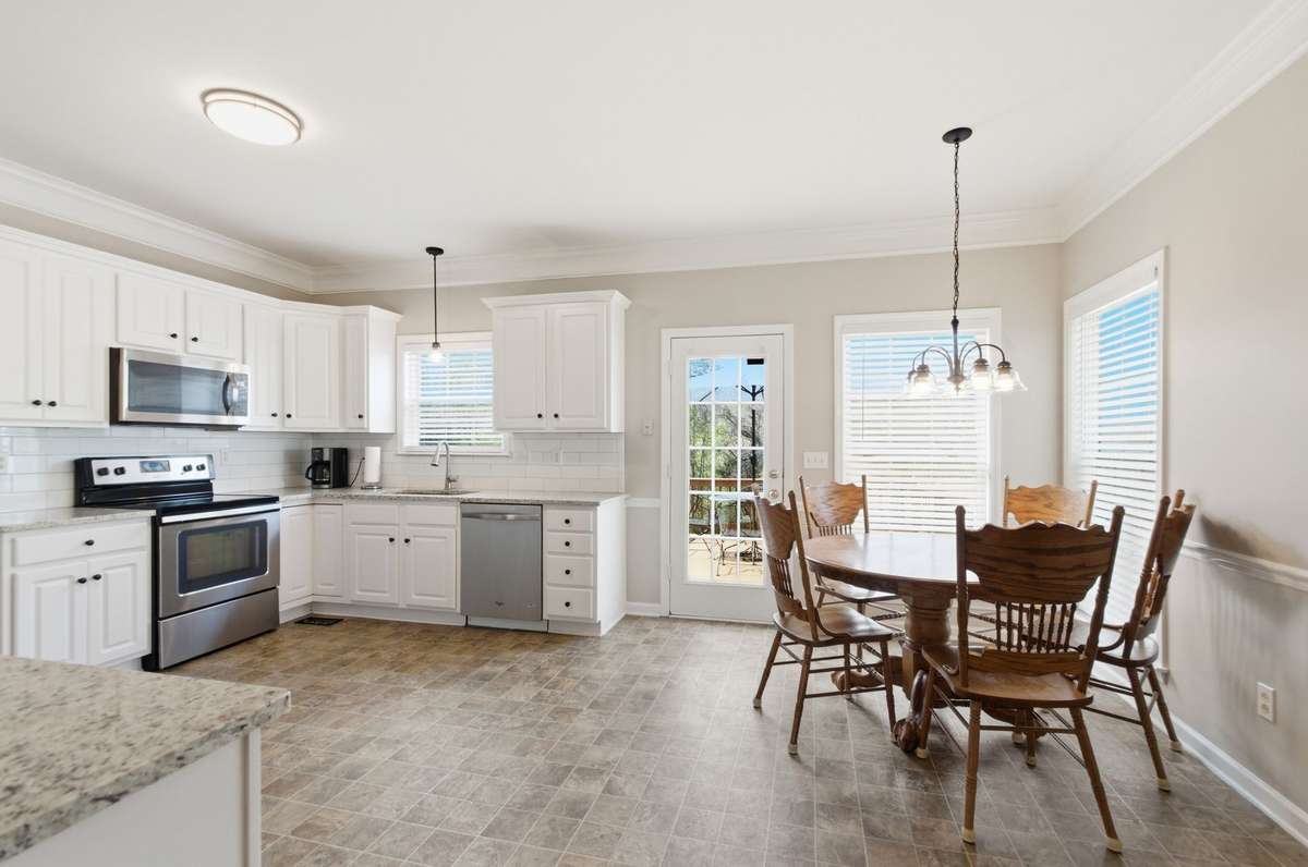 Generous eat-in kitchen with ample cabinet space and a dedicated dining area, offering direct access to the outdoor deck.