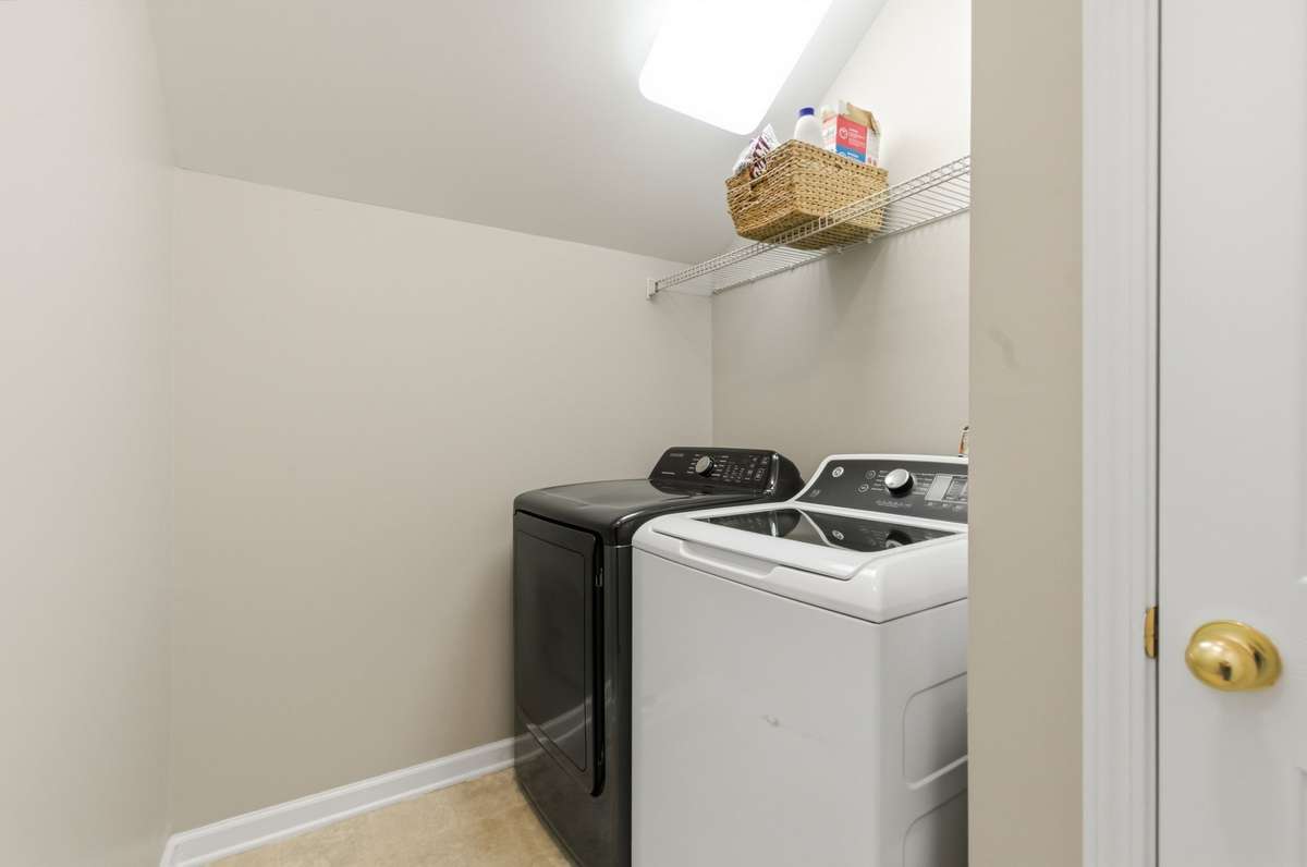 Dedicated laundry space with washer and dryer setup, plus shelving for additional storage.