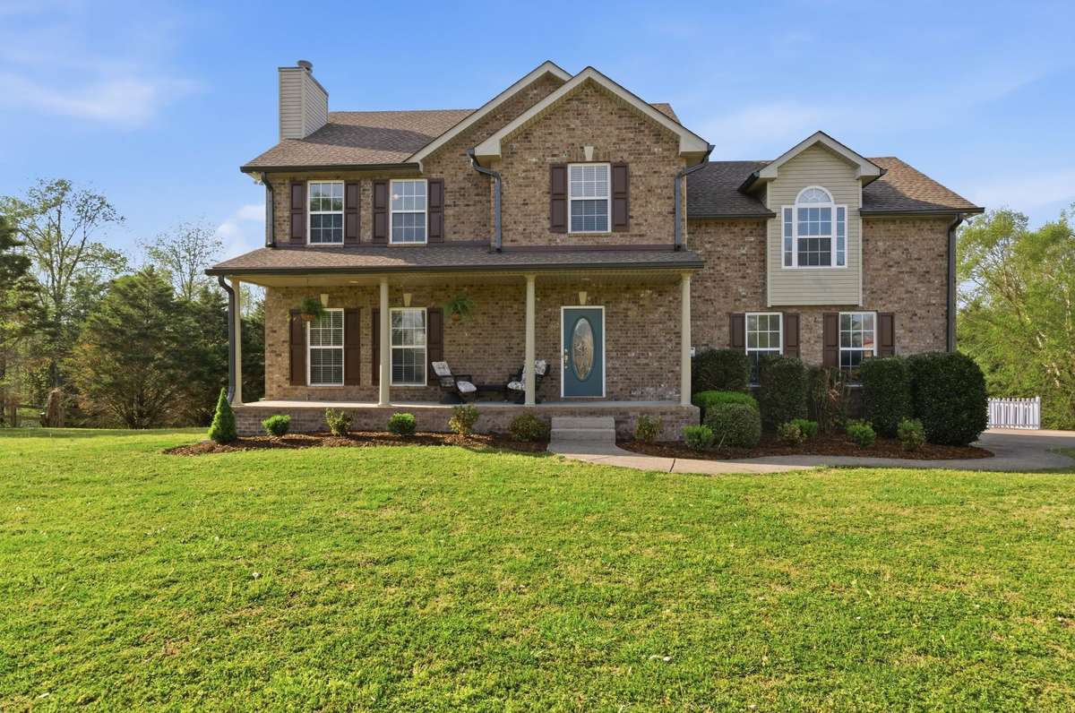 Classic two-story brick exterior with inviting curb appeal, highlighted by a covered front porch and neatly maintained landscaping.