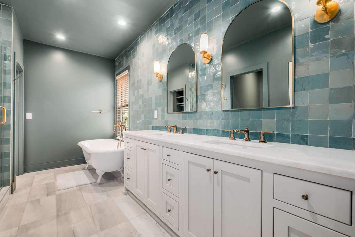 View of primary bath with dual vanities, tile accent wall, separate tub / separate shower, linen closet, and door to the WC.