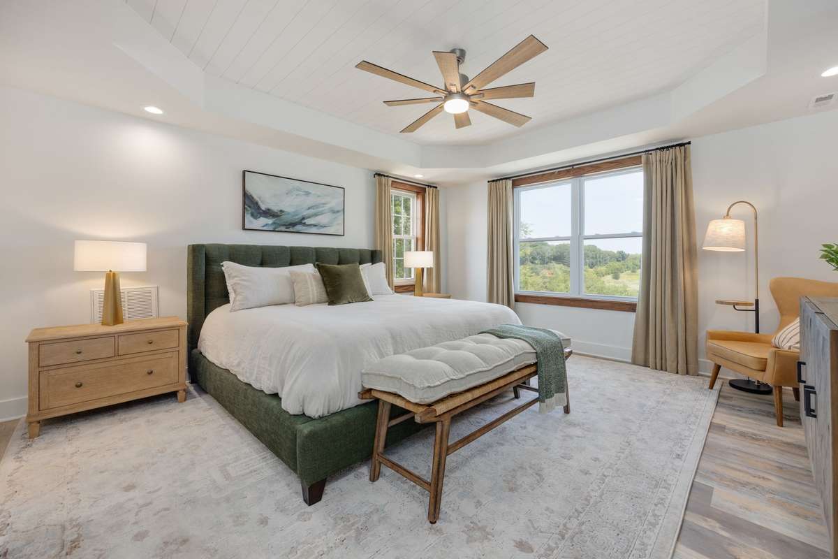 The main-level primary suite is a true retreat, featuring a tray ceiling, double vanities, a soaking tub, a dramatic floor-to-ceiling tile shower, shiplap accent walls, and a walk-in closet with laundry connections for ultimate convenience.