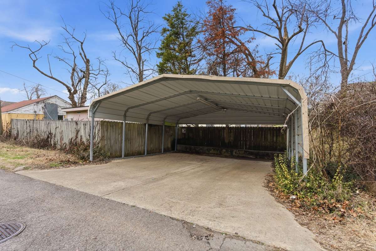 A metal carport in the rear provides sheltered off-street parking.