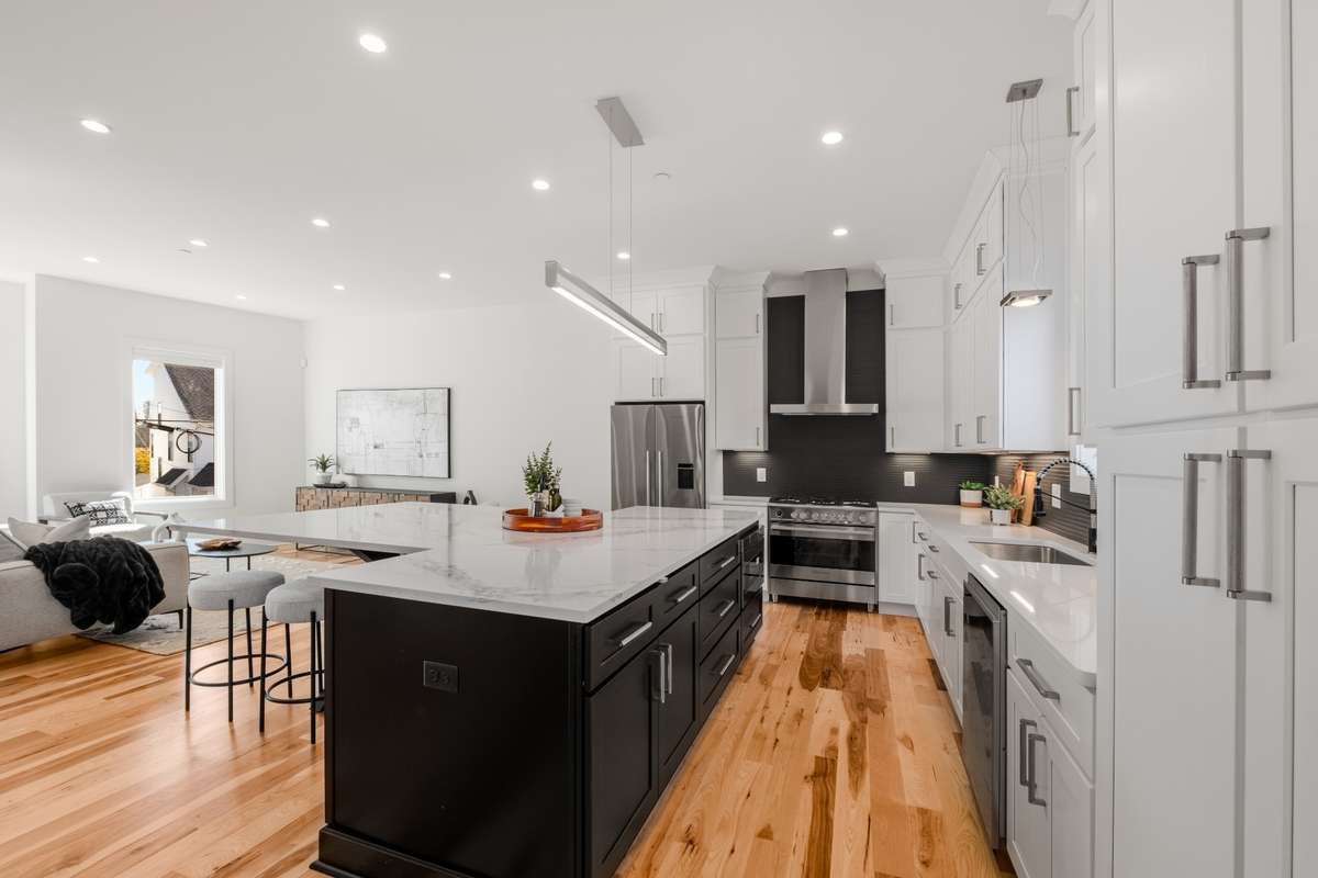 Elegant and modern, the kitchen features Fisher & Paykel appliances, including a refrigerator and gas range, and is accentuated by the contrast of dark and crisp white cabinetry against the warm, hickory floors.