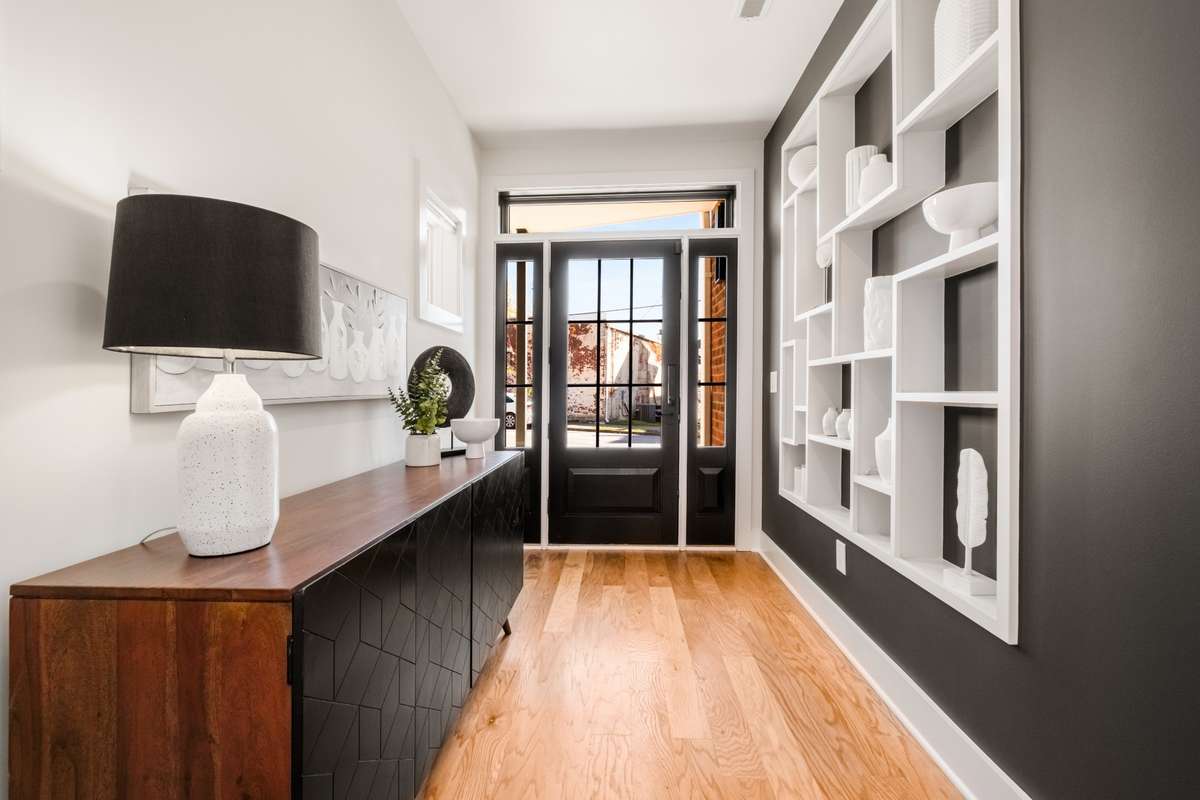 The dramatic black accent wall is beautifully complemented by white shelves for storage or styling, creating an unforgettable first impression.