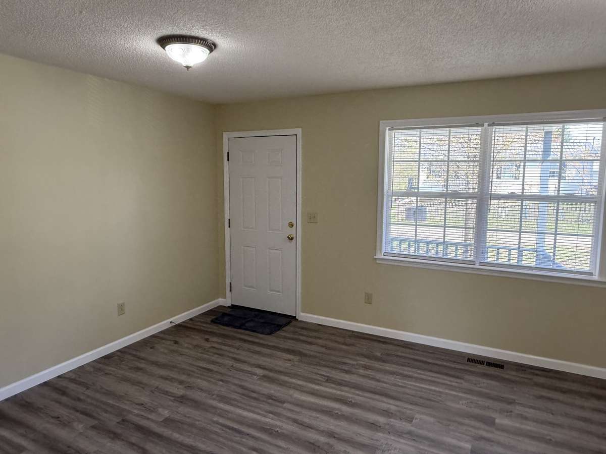 Living room with front entry and double window, new flooring.