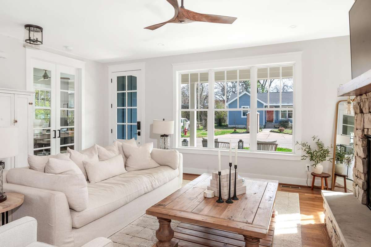 Bright living space with expansive windows, hardwood flooring, and a cozy fireplace.