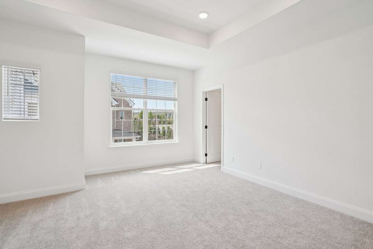 Spacious primary suite featuring a tray ceiling and abundant natural light, creating a bright and relaxing retreat.