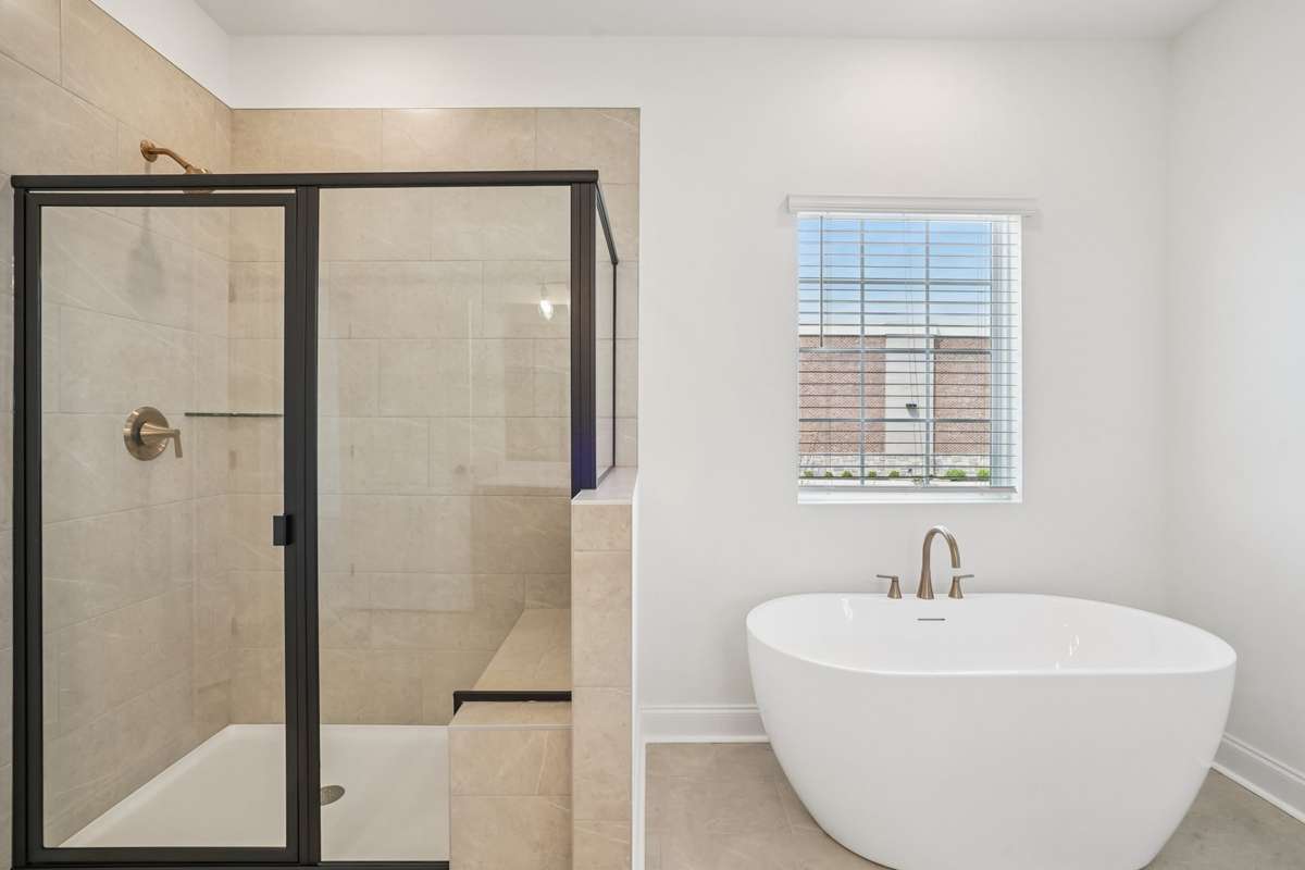 Luxurious primary bath with a spacious shower featuring a built-in bench and a freestanding tub, combining comfort and spa-like elegance.
