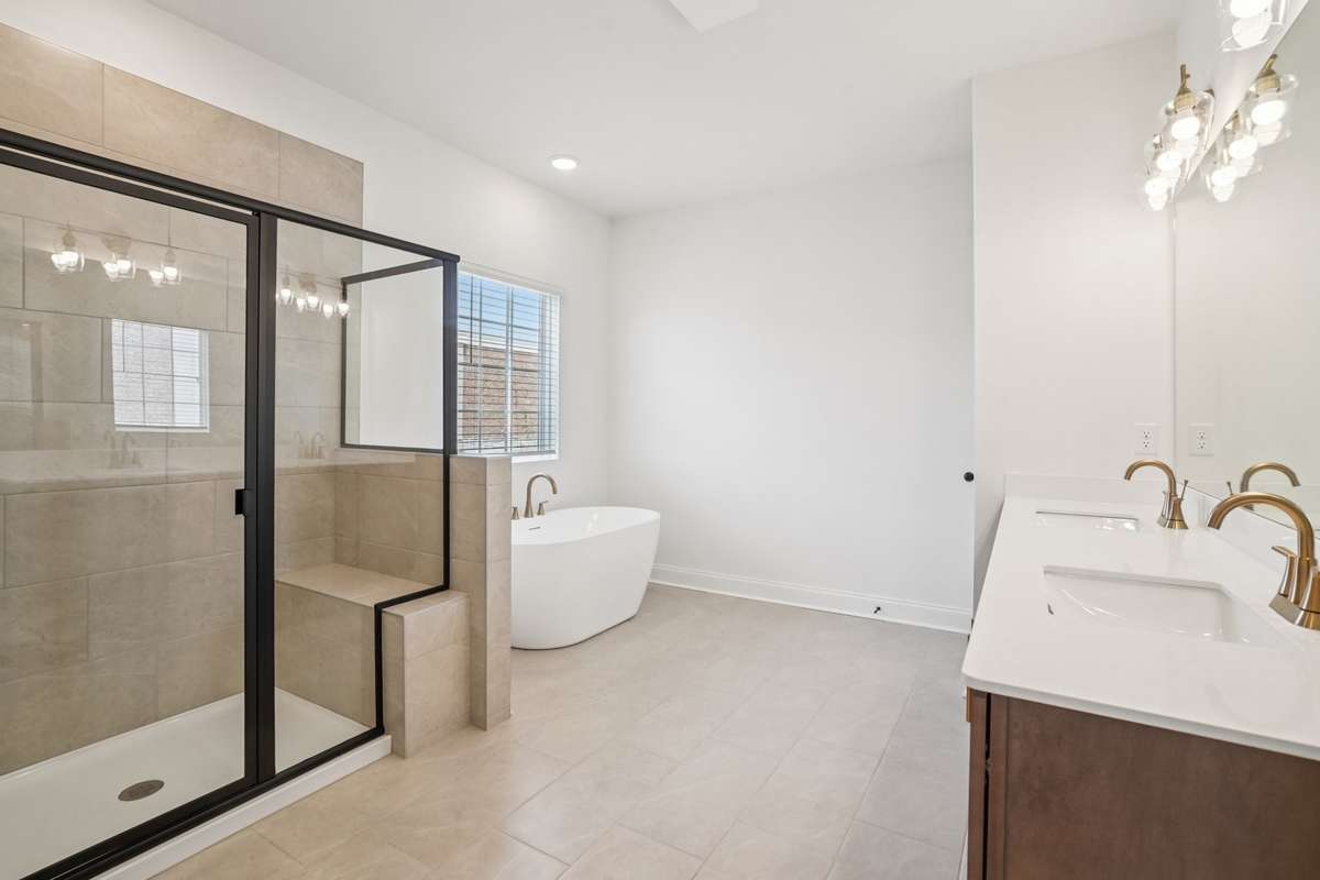 Primary bathroom featuring tile flooring, dual sinks with quartz countertops, and a clean, modern design perfect for everyday comfort.