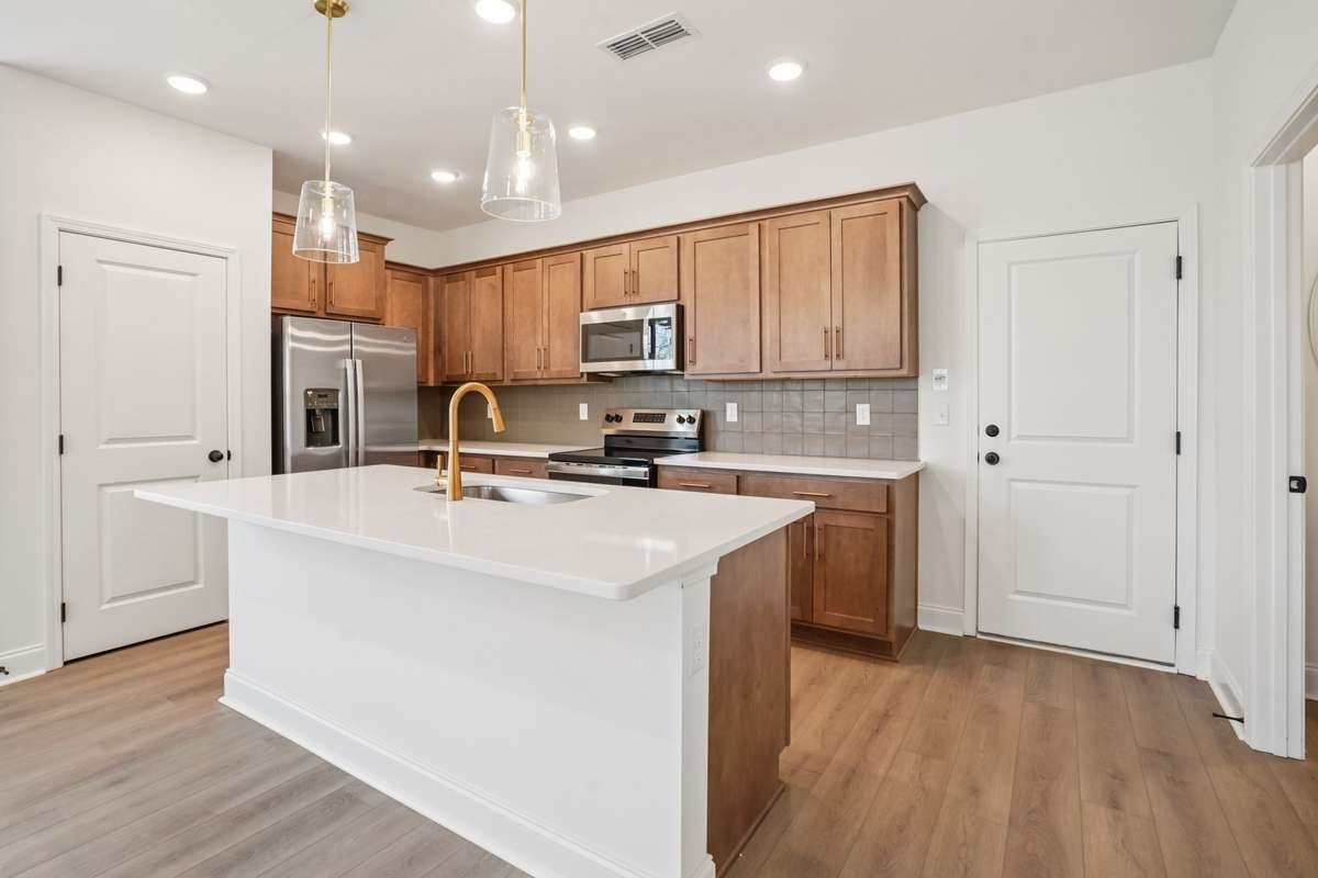 The kitchen showcases wood-toned cabinetry with soft-close doors, quartz countertops, and a stylish 5" x 5" backsplash for a warm, modern finish.