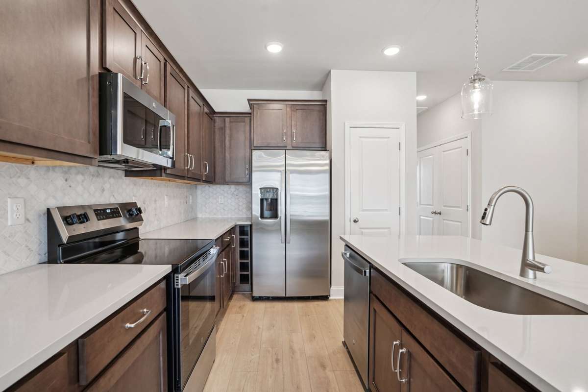 Stainless steel appliances, including a refrigerator, and pendant lighting complete the kitchen, adding a sleek, contemporary touch to this stylish space.
