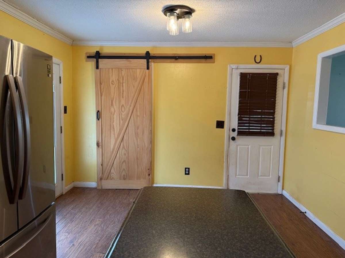 A view from the kitchen to the dining area.  The laundry room is behind the barn door.
