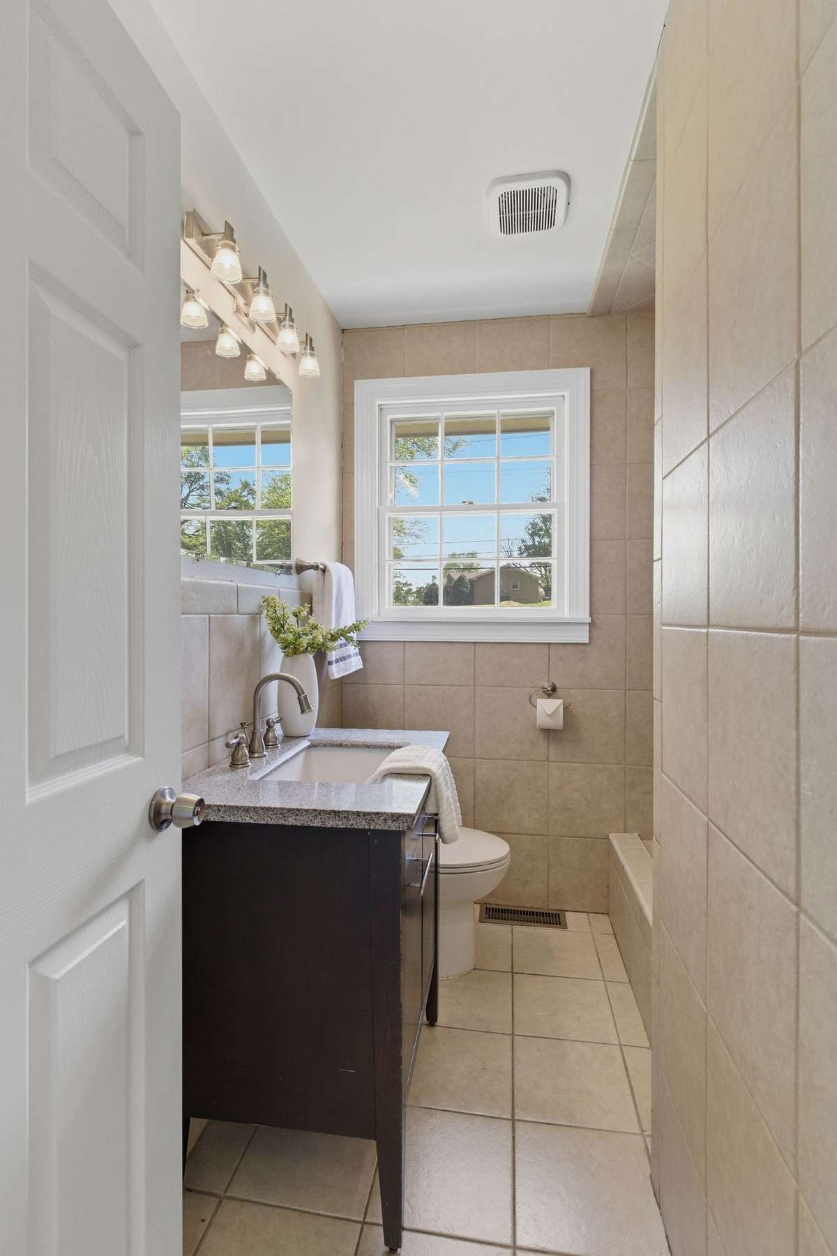All tile with wooden vanity and oversized mirror.