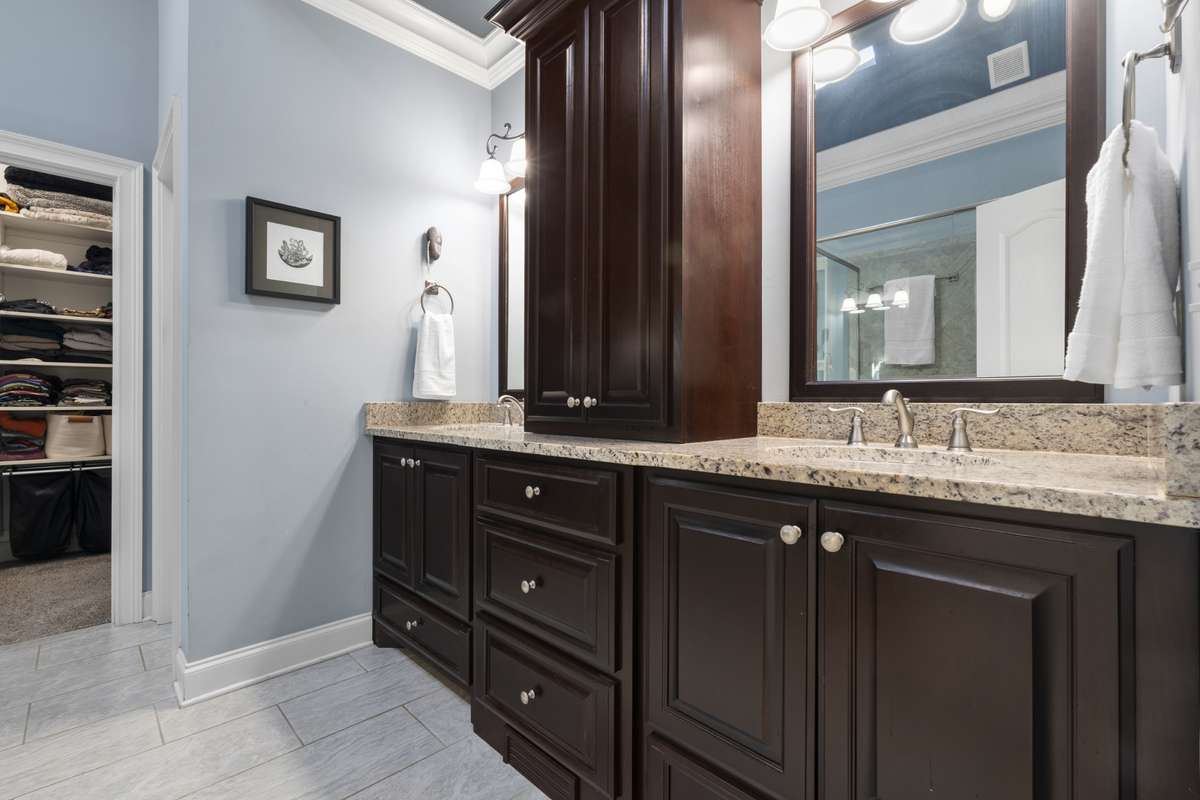 Handsome cabinetry in the primary bath offers lots of storage for the double vanity.