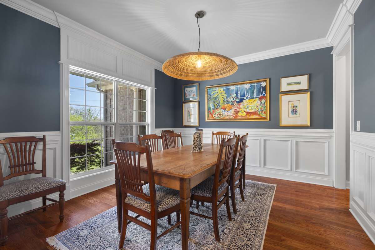 Formal dining room with custom wainscoting and a large picture window overlooking the front yard.