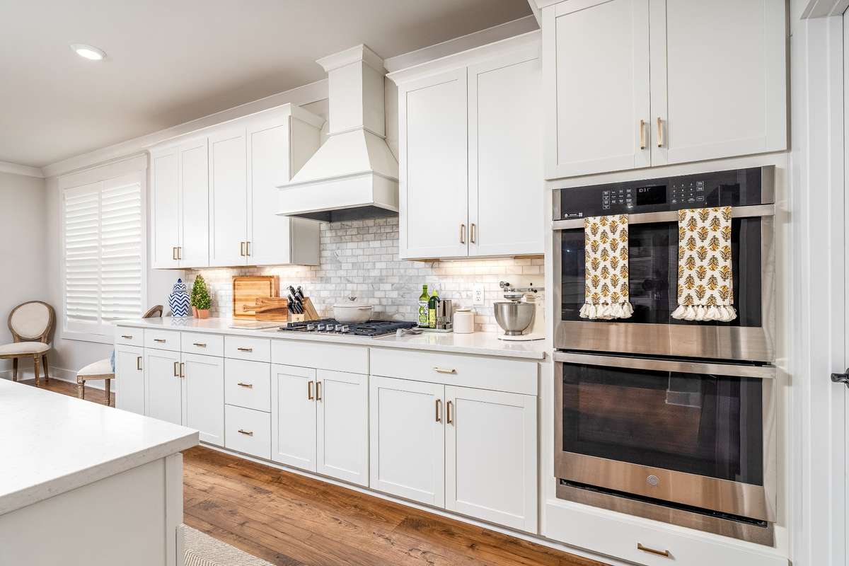 An abundance of cabinets, Tiled backsplash, custom stove hood, double SS ovens