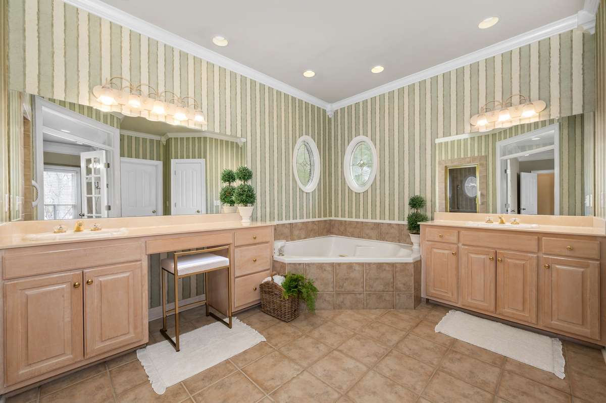 Spacious primary bath with double vanities, a soaking tub and walk-in tiled shower.