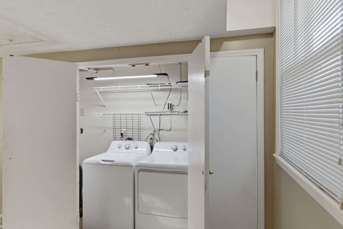A view of the Spacious DEEP (in width) Laundry Room, with only two of the bi-fold doors open in the photo.  There's lots of space on both sides of the washer & dryer for additional storage.