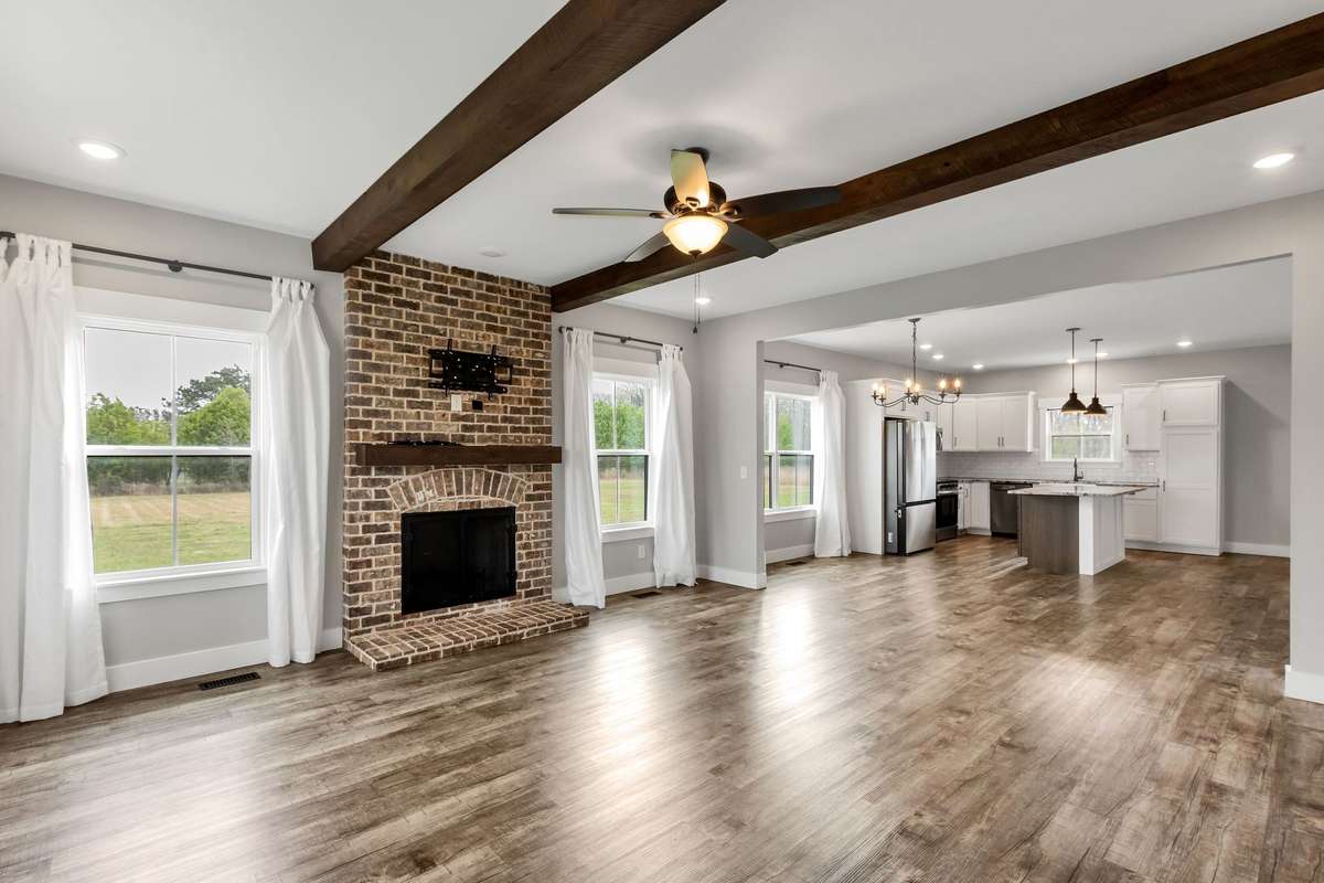 Living room features a wood burning fireplace, LVP flooring and stained wooden beams