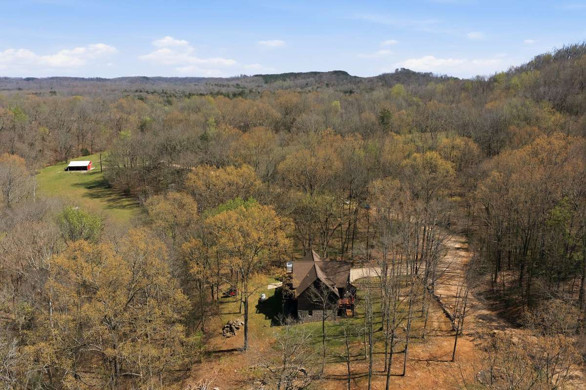 Aerial view showing the log home, pastureland, and barn/shop