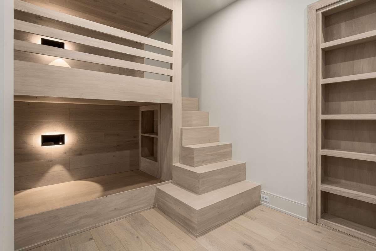 Custom built-in bunks with integrated shelving and stair access maximize space while adding architectural interest and everyday function.